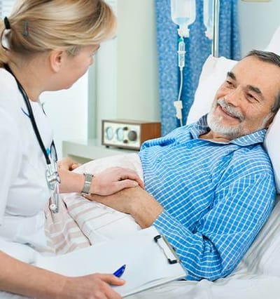 Nurse interacting with a smiling resident in bed