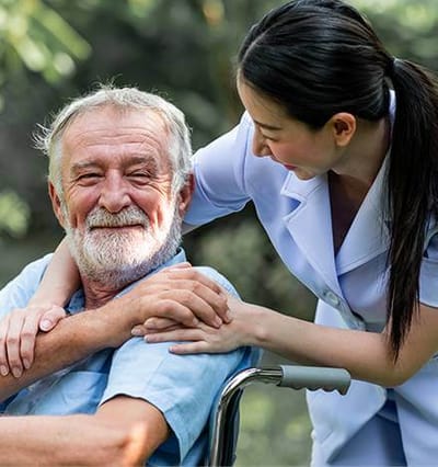 A caregiver smiling with a resident in a garden