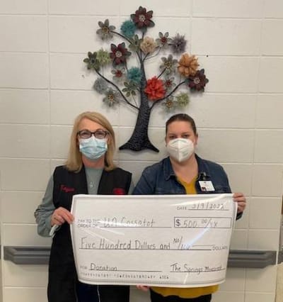 Staff members holding a donation check in a hallway