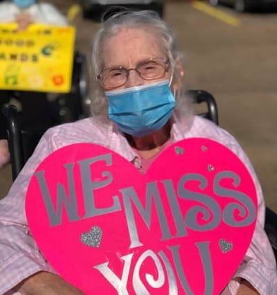 Resident holding a sign that says 'We Miss You'