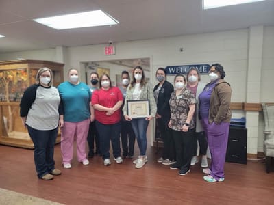Staff members posing with an award in the facility