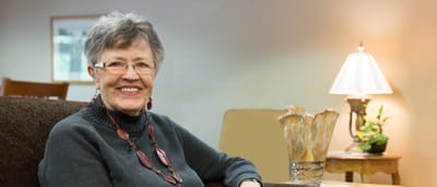 Smiling resident sitting in a cozy lounge area
