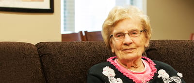 A resident smiling while sitting on a couch in a common area