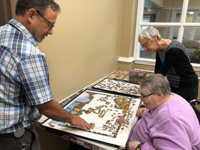 Residents engaged in a puzzle activity with staff assistance