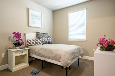 A cozy resident room with a bed and flowers