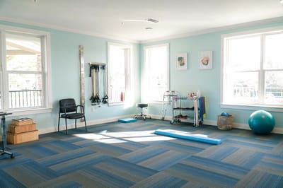 Bright exercise room with equipment and blue flooring