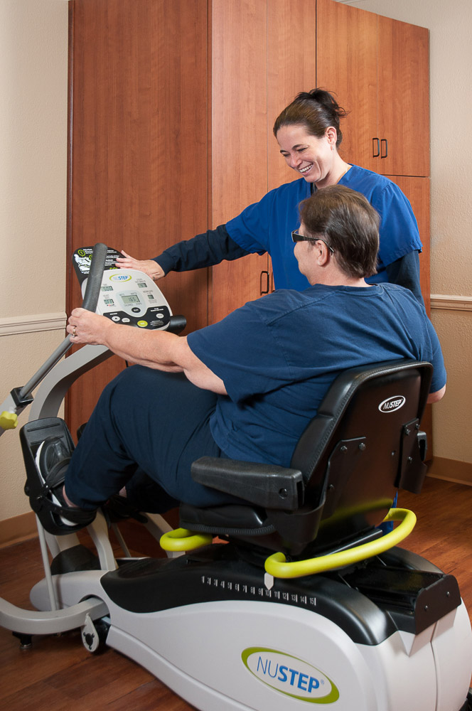 Staff assisting a resident with exercise equipment