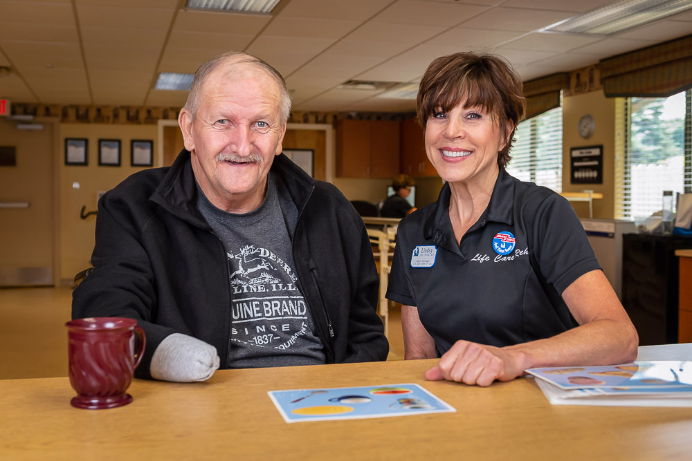 Resident and staff member smiling together at a table
