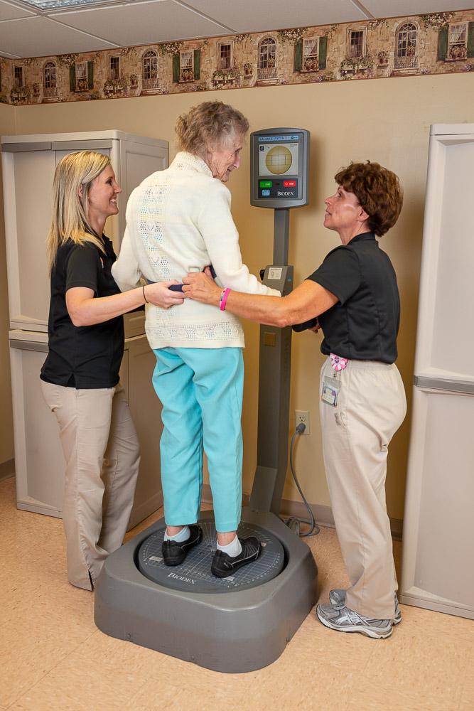 Staff assisting a resident with a weight scale in a facility interior