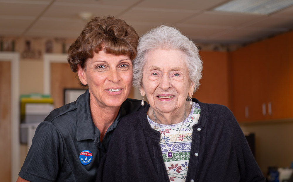 Caregiver and resident smiling together in the activity room