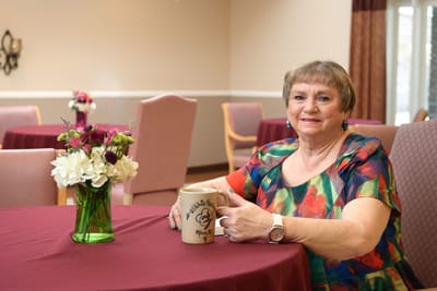 Resident posing with a coffee mug in a common area