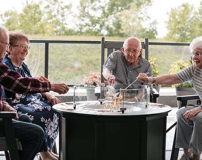 Seniors enjoying an outdoor activity around a fire table