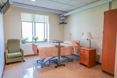 A private resident room with a hospital bed and chair