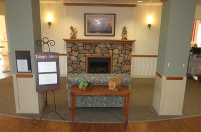Cozy common area with a stone fireplace and menu board