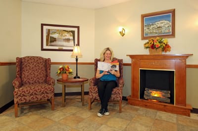 Woman reading in a cozy common area with a fireplace