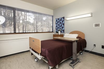 A private resident room with a bed and side table