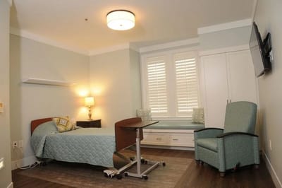 Private room in a senior living facility with a bed and seating area