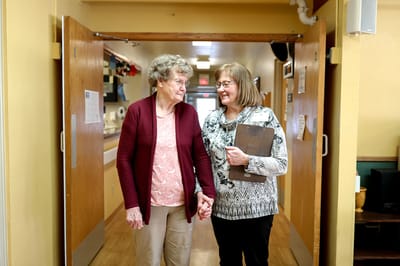 Two women walking and chatting in a facility hallway
