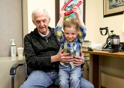 An elderly man interacting with a young boy indoors