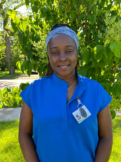 Staff member smiling outdoors by a tree