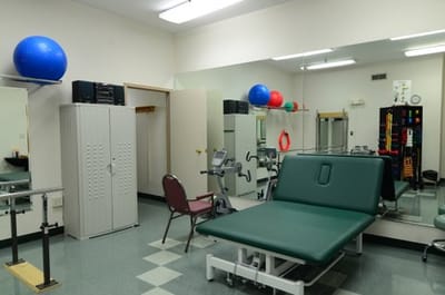 Physical therapy room with equipment and mirrors