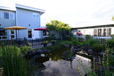 Outdoor space with a pond, chairs, and umbrellas