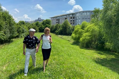 Couple walking through a green outdoor area near the facility
