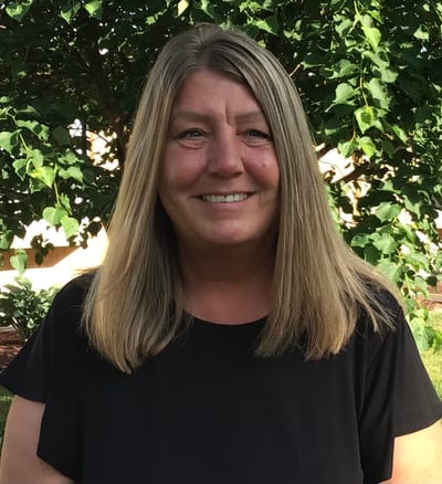 A smiling staff member outdoors in a garden area