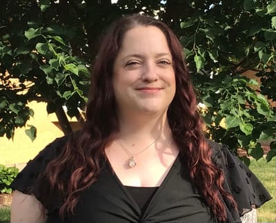Staff member posing outdoors with greenery