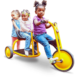 St Ann Center for Intergenerational Care, memory care in Milwaukee, WI — Children riding a large yellow tricycle together