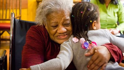 A resident embracing a young child in a warm moment