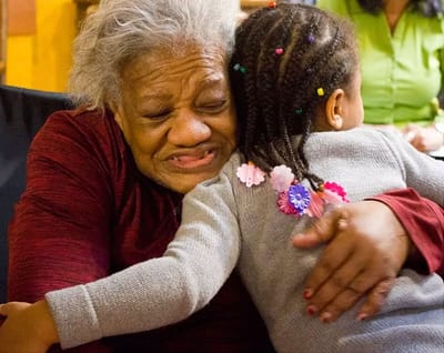 A resident hugging a young child in a warm setting.