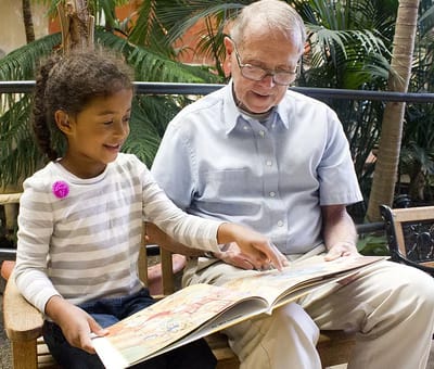 St Ann Center for Intergenerational Care, memory care in Milwaukee, WI — Child and senior man sharing a storybook together