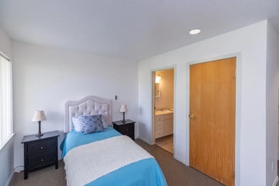 Bright private bedroom with a bed and bathroom access