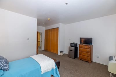 A private resident room with a bed, dresser, and TV