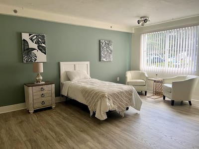 A bright resident room with a bed and seating area