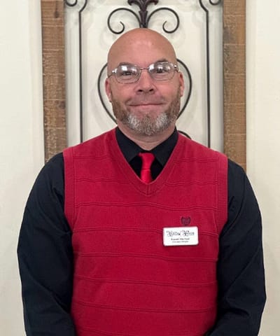 Staff member posing in a uniform with a name tag
