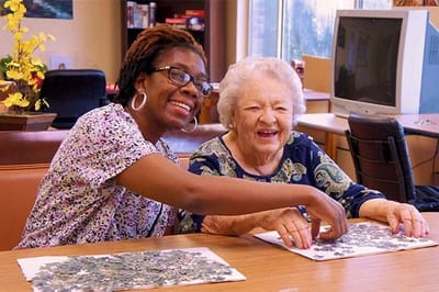 Residents enjoying a puzzle activity with staff help