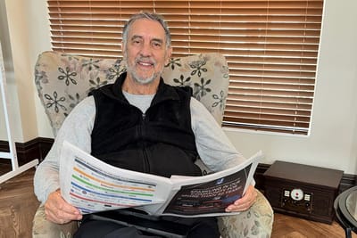 Resident reading a newspaper in a cozy chair