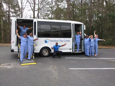 Group of staff by the facility van, smiling and waving.