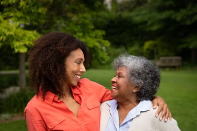 A young caregiver smiling with a resident in a garden