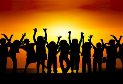Silhouettes of children celebrating against a sunset
