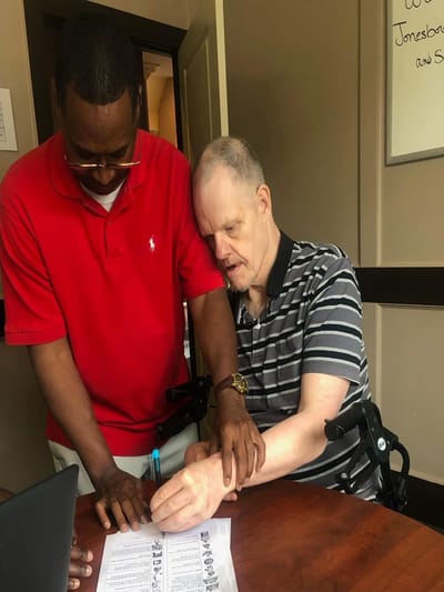 Staff assisting a resident with paperwork in an indoor setting