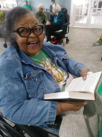 Resident smiling while reading a book in a common area