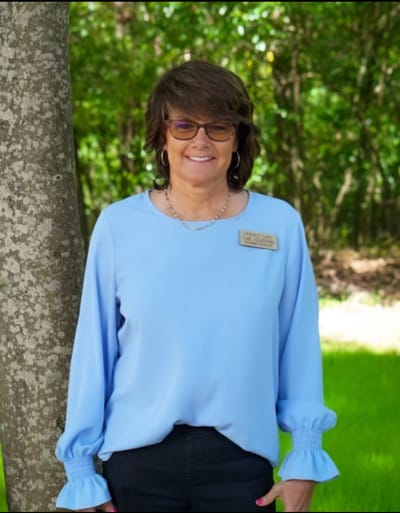 Staff member posing outdoors near a tree