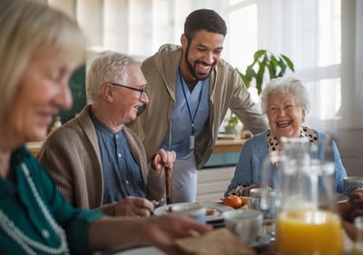 Sarah Adult Day Services, nursing home — Seniors enjoying breakfast with a caregiver in a dining area
