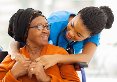 Sarah Adult Day Services, nursing home — Caregiver assisting senior woman in a wheelchair