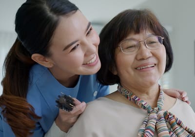 Sarah Adult Day Services, nursing home — Caregiver styling hair for a smiling elderly woman