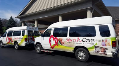 Sarah Adult Day Services, nursing home — Two vans with SarahCare branding parked outside a building