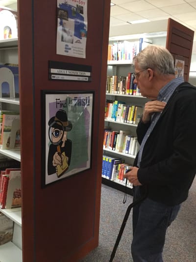 Senior resident engaging with a poster in a library setting